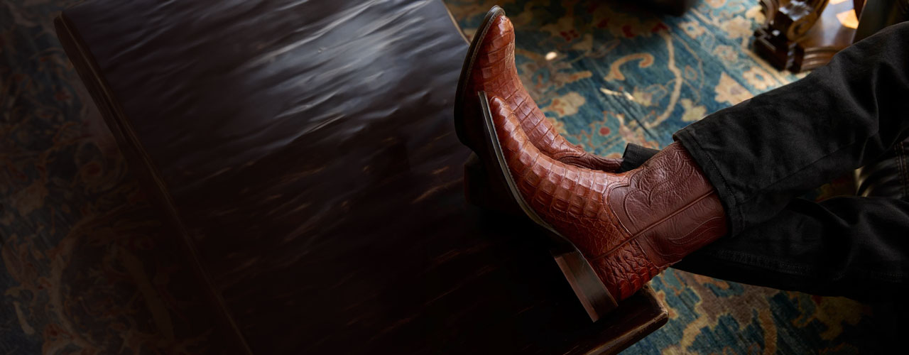 A man sitting on a couch with his feet up wearing a pair of Tony Lama boots.